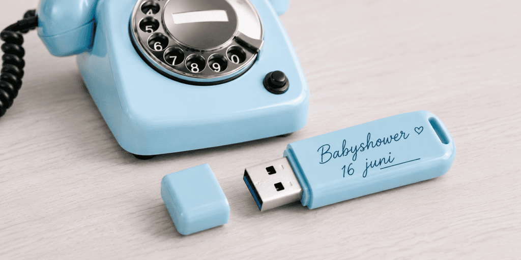 USB-stick met ingesproken babyshower berichten naast een lichtblauwe EventTelefoon als audiogastenboek voor 16 juni.