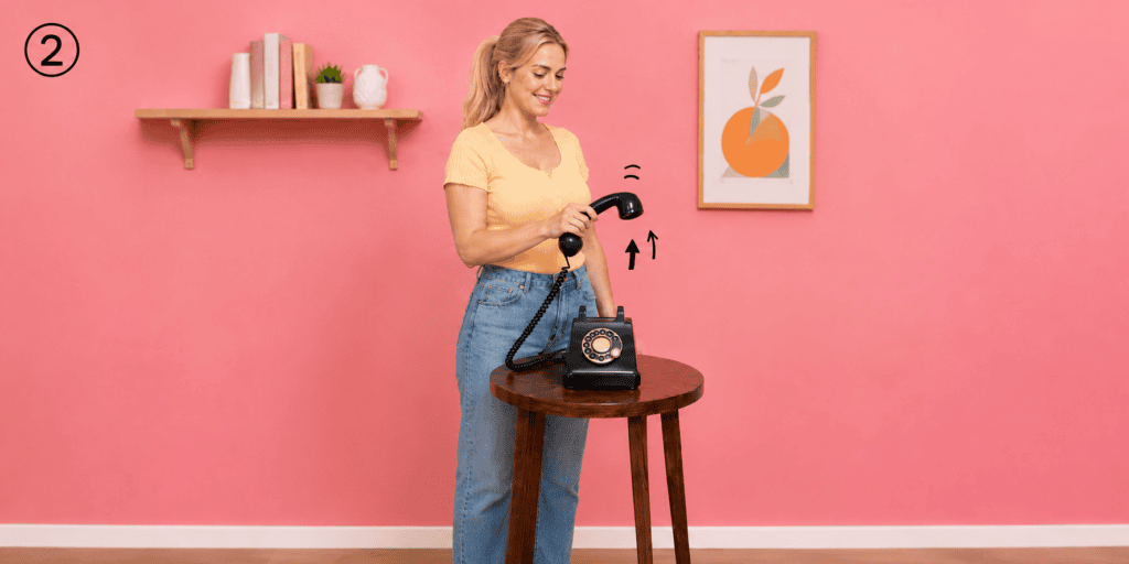 Vrouw pakt de hoorn van een zwarte retro telefoon op om een bericht in te spreken voor het audiogastenboek.