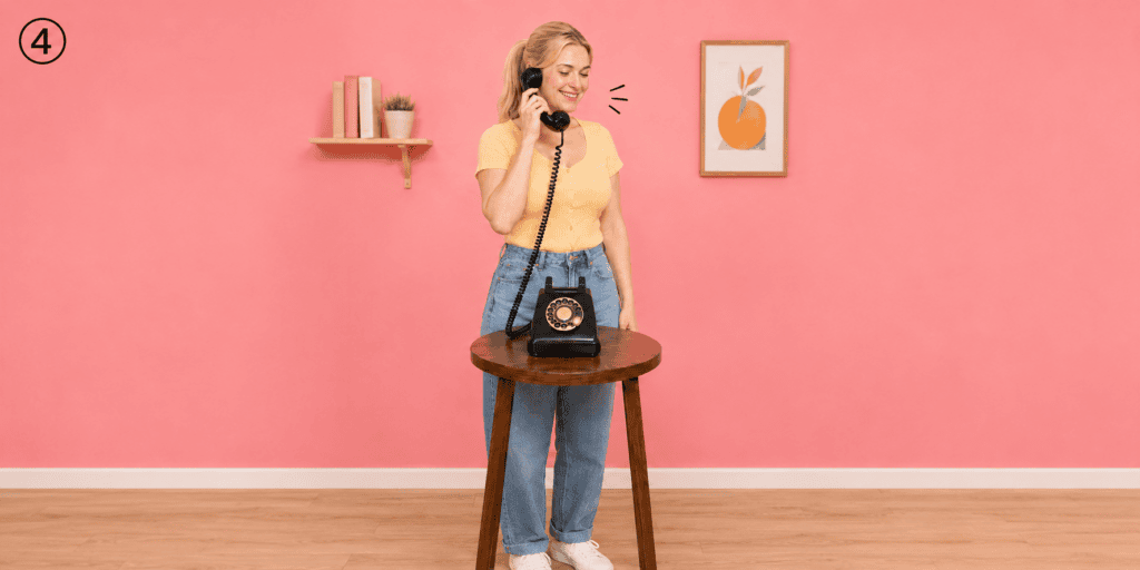 **Alt-tekst:**
Vrouw luistert via een zwarte retro telefoon naar de welkomstboodschap van het audiogastenboek.
