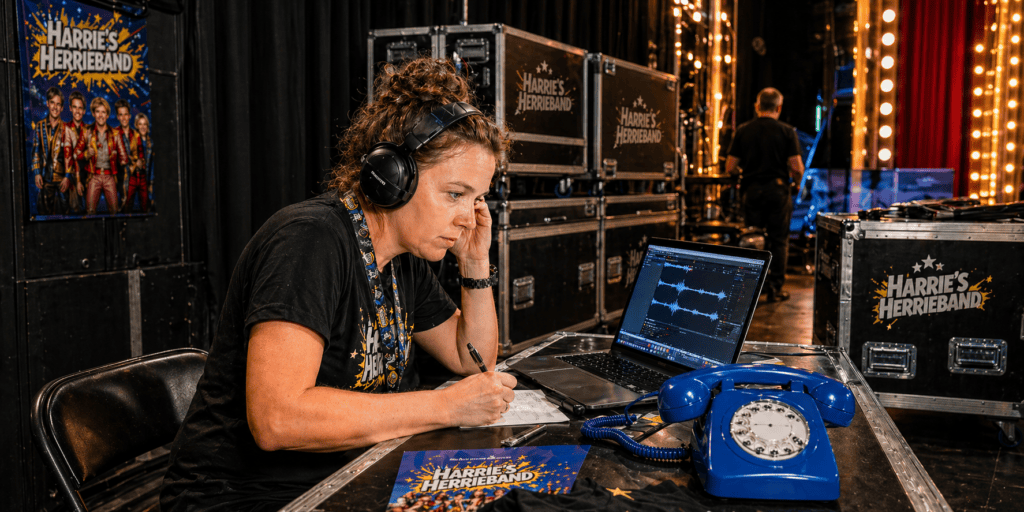 Manager van Harrie’s Herrieband beluistert met een koptelefoon de ingesproken fanberichten naast een blauwe EventTelefoon en selecteert vragen voor de meet & greet.