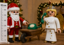 Playmobil kerstman en kerstengel van 63 cm met groene retro telefoon op een kruiwagen tijdens een sfeervolle zakelijke kerstborrel.